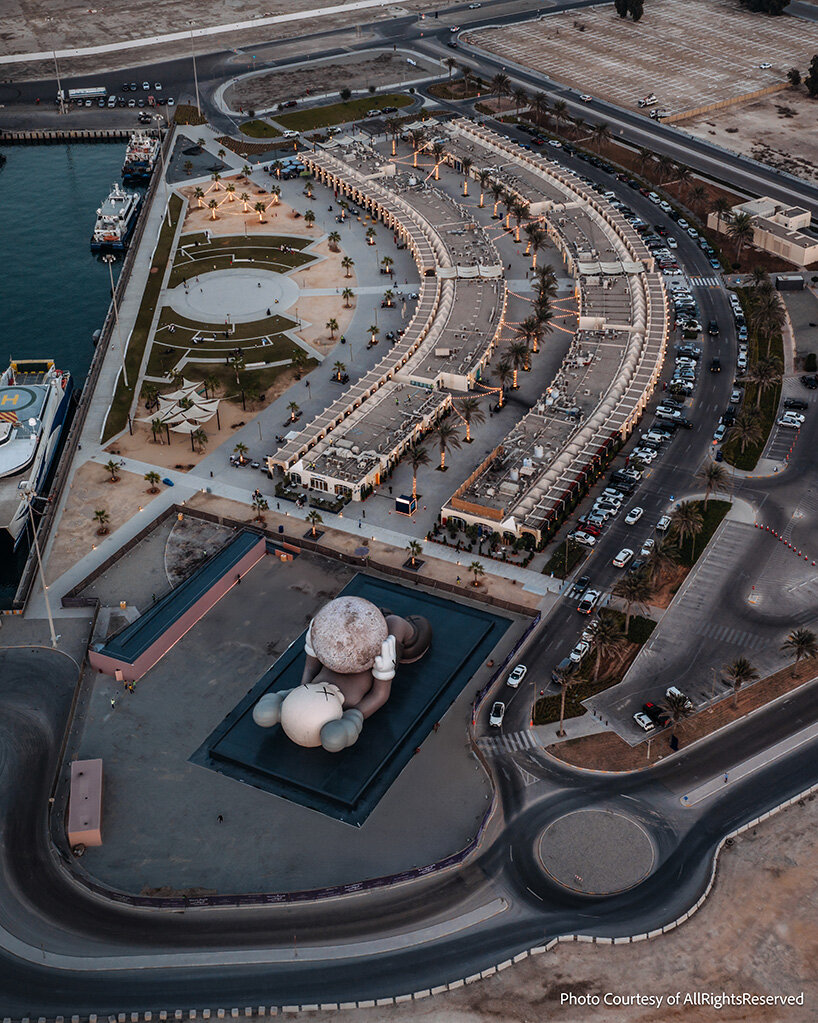 KAWS의 32미터 동반자가 아부다비 해안가를 따라 빛나는 달을 들어올리고 있습니다